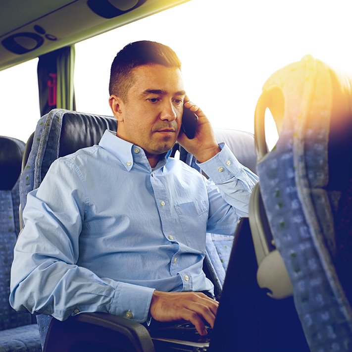 A passenger uses a laptop on a bus